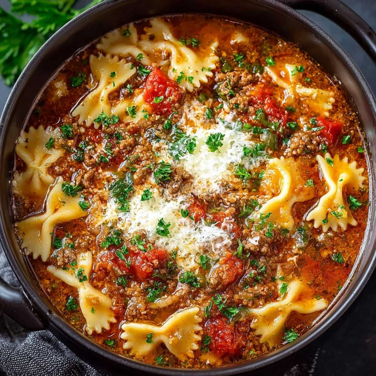 Easy Lasagna Soup in a white bowl on a marble countertop, showcasing its rich tomato broth, wavy lasagna noodles, and melting three-cheese topping.