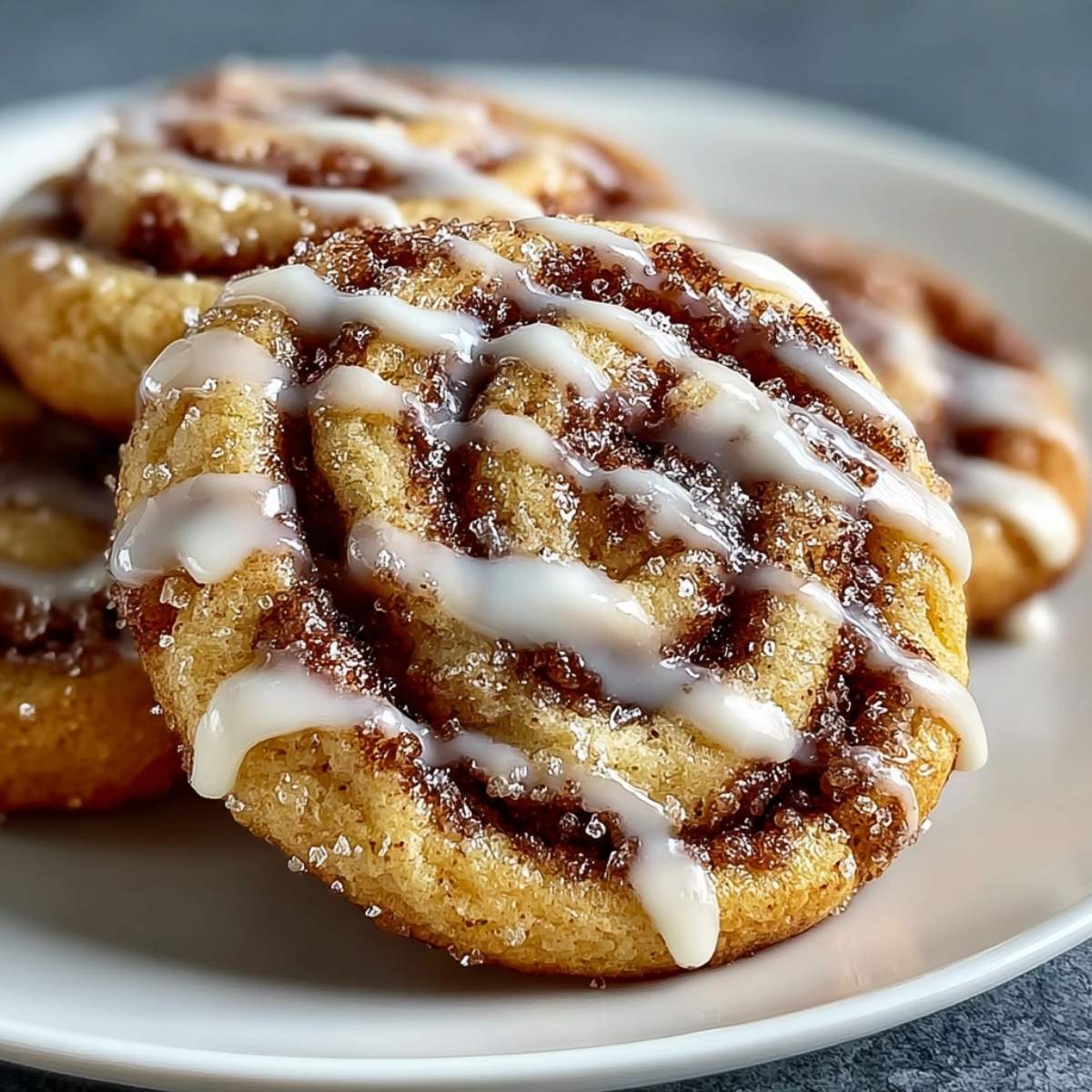 Close-up of irresistible cinnamon roll cookies showing soft sugar cookie texture, caramelized cinnamon swirls, and glossy vanilla icing.