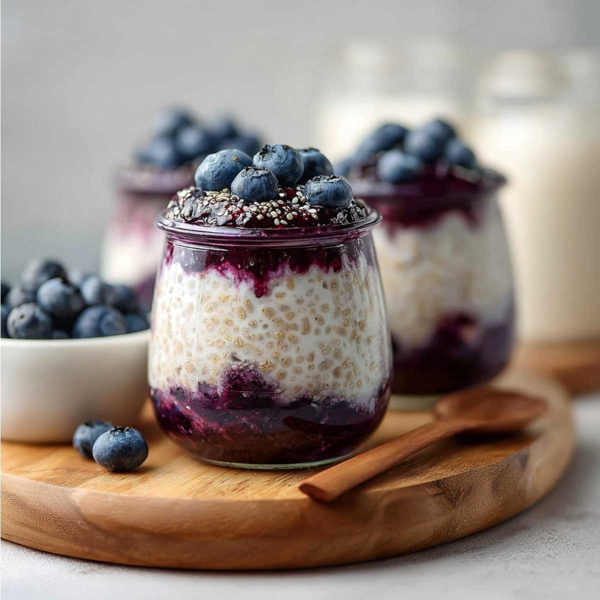 Easy Blueberry Overnight Oats 11 Final blueberry overnight oats with creamy yogurt oats, chia seeds and fresh blueberries served in glass jars on wooden board