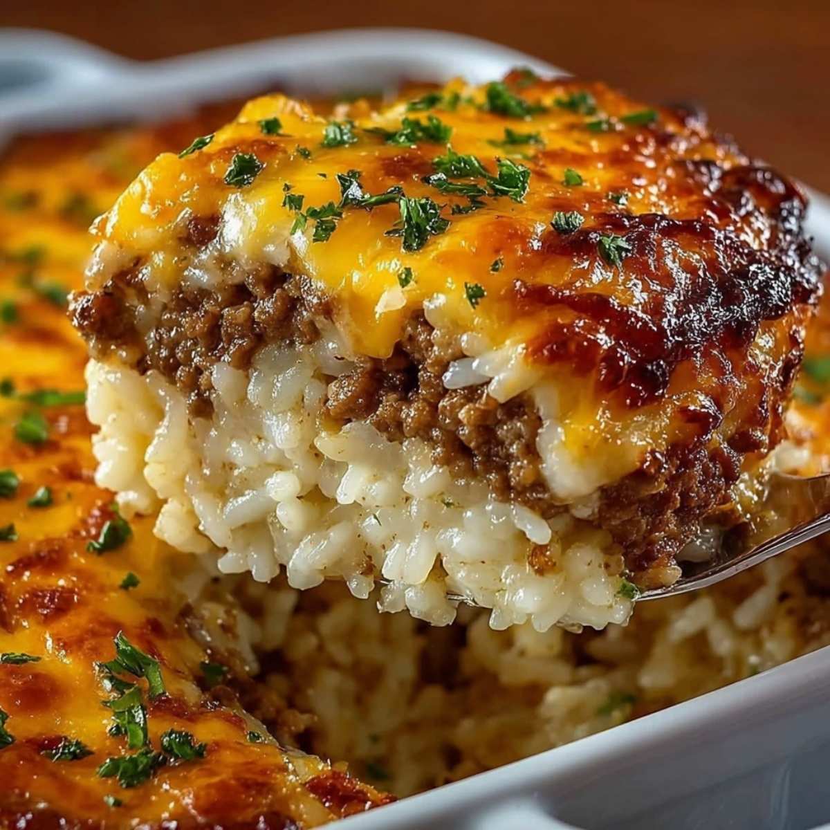 Hamburger rice casserole on a white baking dish, showcasing fluffy rice, seasoned ground beef, and a golden melted cheese topping.